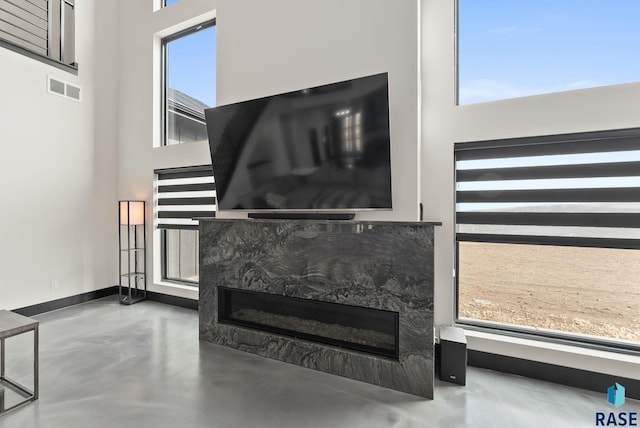 living room with concrete flooring and a high ceiling