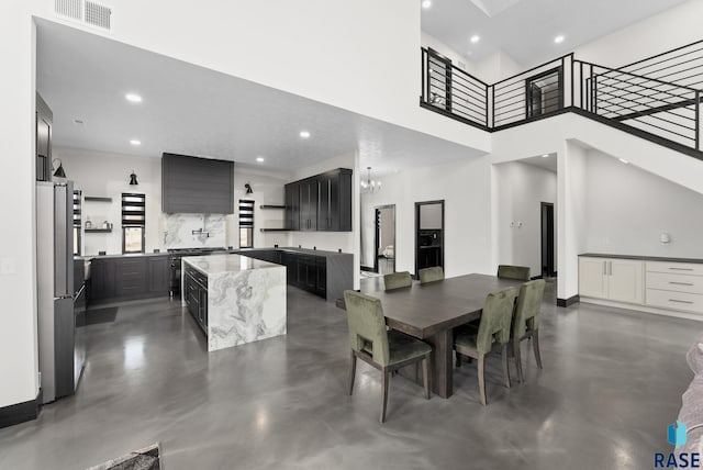 dining area featuring an inviting chandelier and a towering ceiling