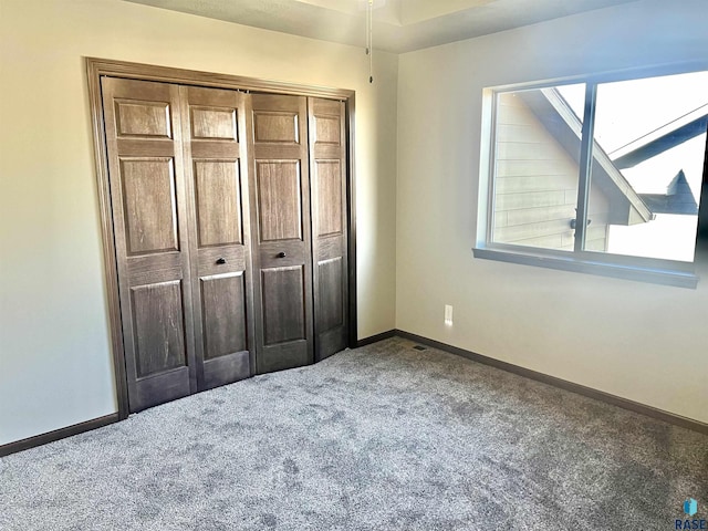 unfurnished bedroom featuring multiple windows, a closet, and carpet flooring