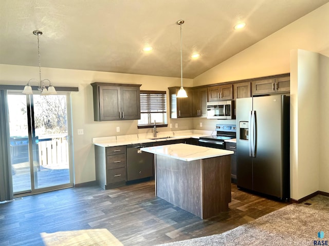 kitchen with sink, vaulted ceiling, hanging light fixtures, appliances with stainless steel finishes, and a kitchen island