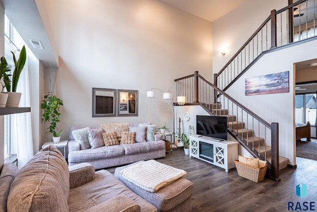 living room featuring a towering ceiling and dark wood-type flooring