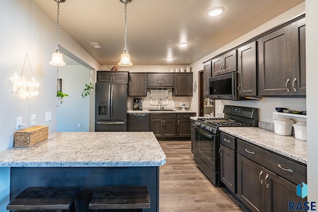 kitchen featuring dark brown cabinetry, sink, decorative light fixtures, and black appliances