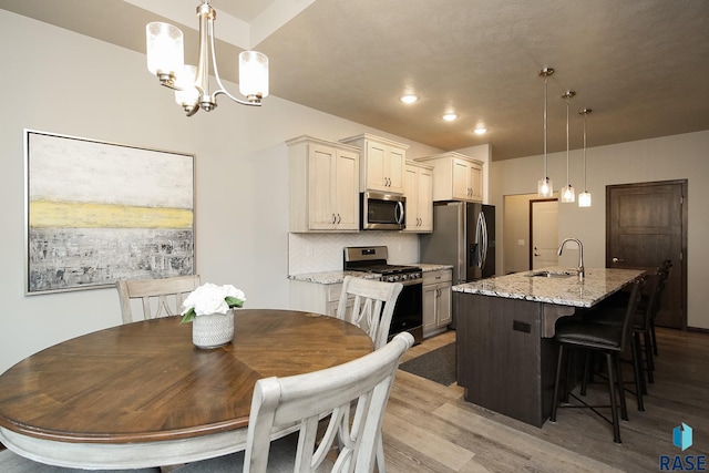 dining room with an inviting chandelier, sink, and light hardwood / wood-style flooring