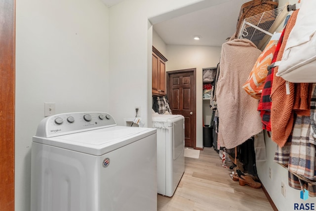 laundry room with cabinets, washer and dryer, and light wood-type flooring