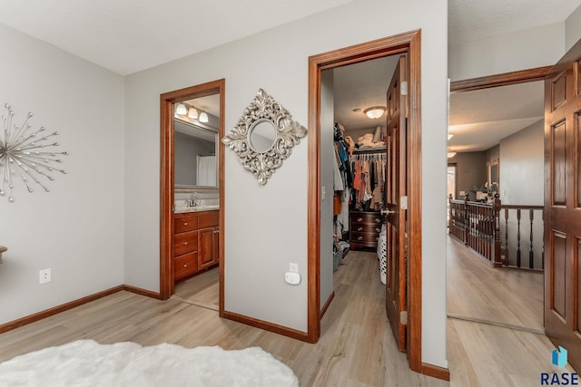 hallway featuring sink, a textured ceiling, and light wood-type flooring