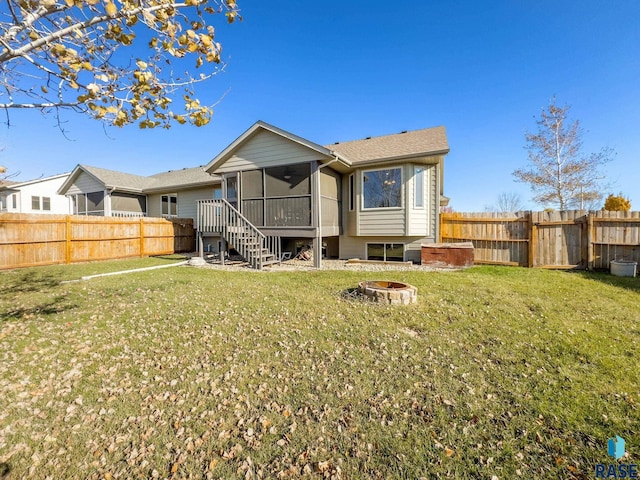 back of property featuring an outdoor fire pit, a yard, and a sunroom