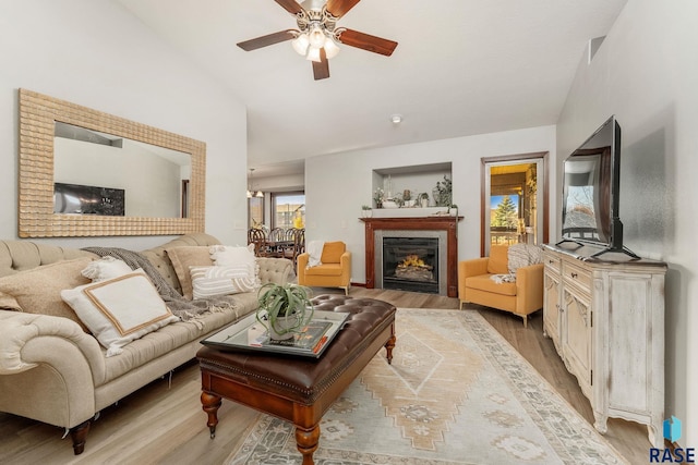 living room with ceiling fan, lofted ceiling, and light wood-type flooring