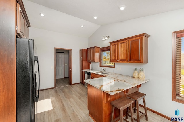 kitchen featuring black refrigerator, dishwasher, lofted ceiling, a kitchen bar, and kitchen peninsula