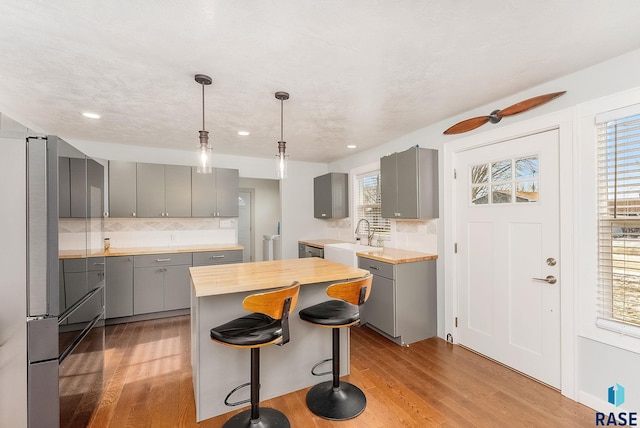 kitchen featuring sink, gray cabinetry, a center island, light hardwood / wood-style floors, and backsplash