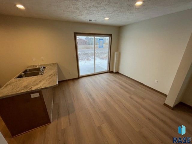 interior space featuring sink, a textured ceiling, and light hardwood / wood-style floors