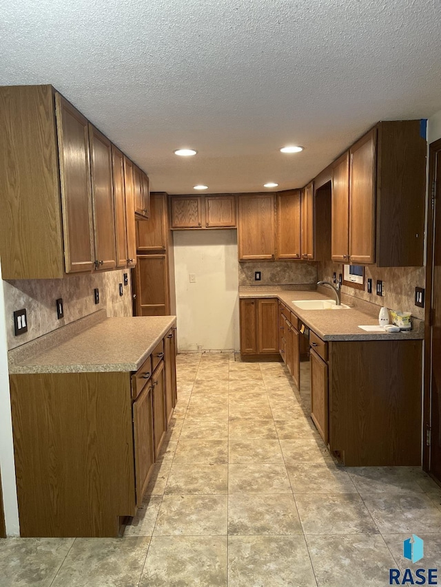 kitchen featuring sink, decorative backsplash, light tile patterned floors, and a textured ceiling