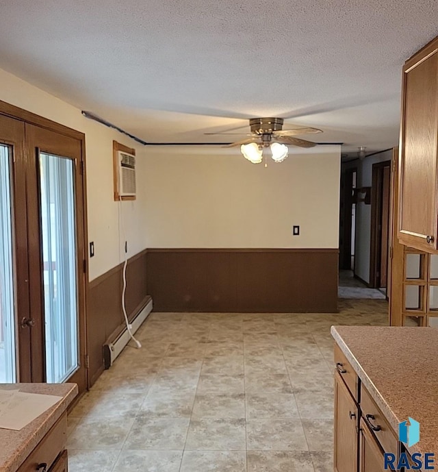 interior space with a baseboard radiator, a wall mounted AC, ceiling fan, a textured ceiling, and french doors