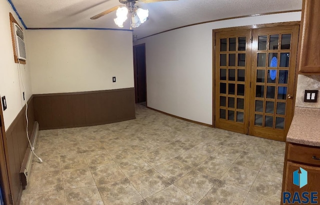 unfurnished room with ornamental molding, wooden walls, ceiling fan, and a textured ceiling