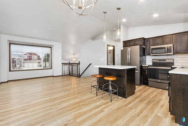 kitchen with a kitchen bar, light hardwood / wood-style flooring, a kitchen island, pendant lighting, and stainless steel appliances