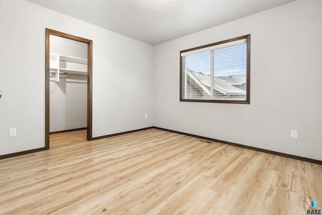 unfurnished bedroom featuring a walk in closet, light wood-type flooring, and a closet