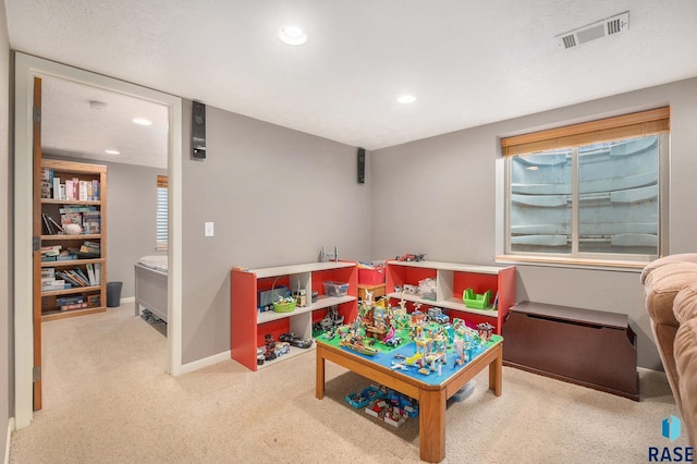 playroom featuring light colored carpet and a textured ceiling