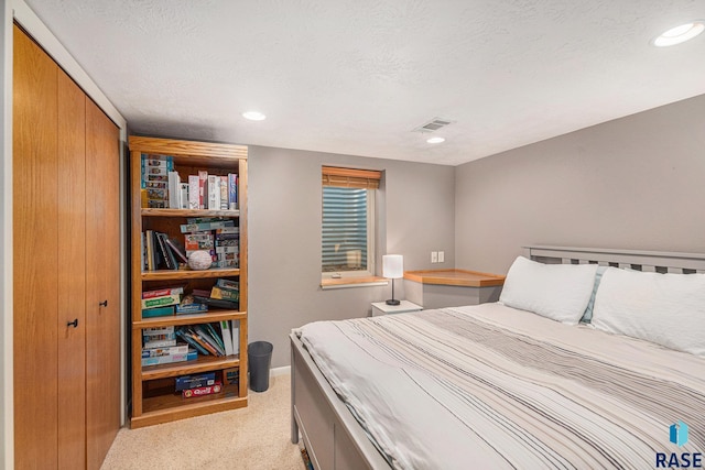 bedroom featuring light carpet, a textured ceiling, and a closet