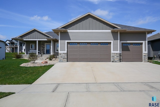 craftsman-style home with a porch, a garage, and a front yard