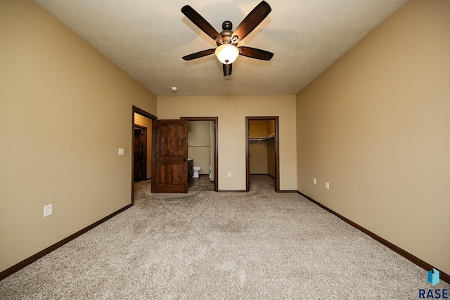 unfurnished bedroom with light carpet, a walk in closet, and ceiling fan