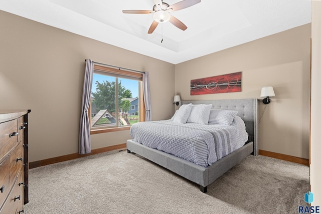 bedroom featuring a raised ceiling, carpet floors, and ceiling fan