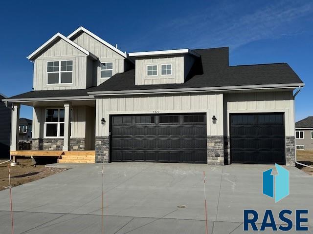 view of front of house with stone siding, concrete driveway, board and batten siding, and an attached garage