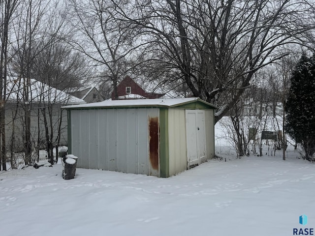 snow covered structure with an outbuilding