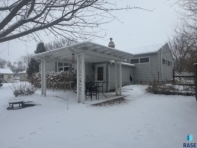 snow covered house featuring a chimney