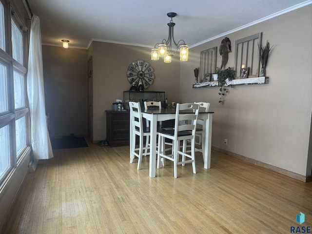 dining room featuring ornamental molding, light wood finished floors, baseboards, and an inviting chandelier