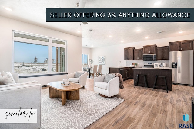 living room featuring sink, light hardwood / wood-style flooring, and ceiling fan