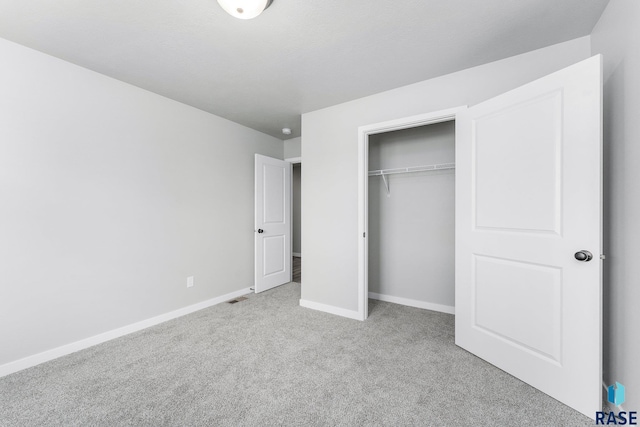 unfurnished bedroom with light colored carpet and a closet