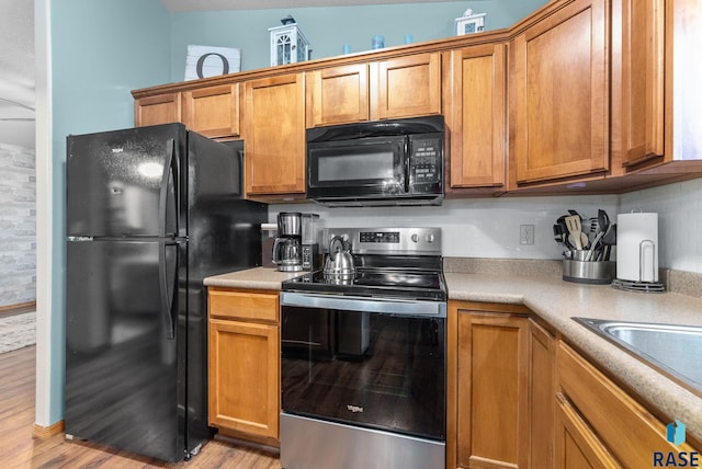 kitchen featuring sink, light wood-type flooring, and black appliances