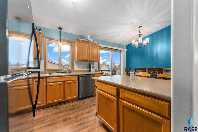 kitchen with sink, black refrigerator, dishwasher, pendant lighting, and light hardwood / wood-style floors