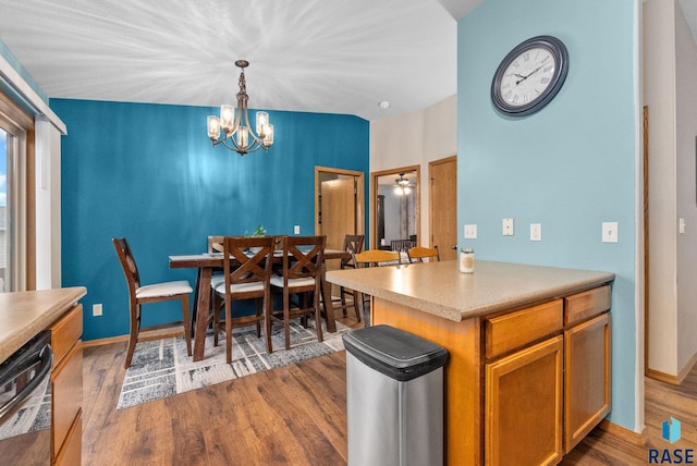 kitchen featuring pendant lighting, wood-type flooring, black dishwasher, and an inviting chandelier