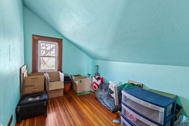 additional living space featuring wood-type flooring, a textured ceiling, and vaulted ceiling