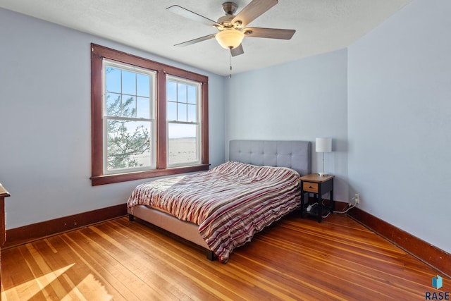 bedroom with hardwood / wood-style flooring, ceiling fan, and a textured ceiling