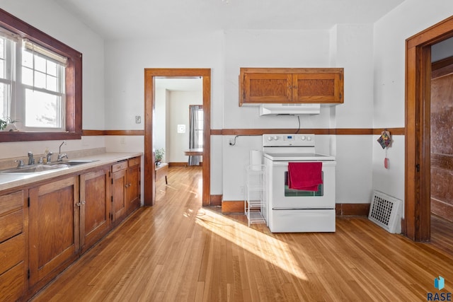 kitchen with light wood-type flooring, sink, and white range with electric stovetop