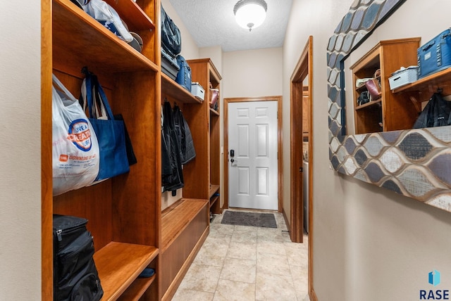 mudroom featuring light tile patterned floors and a textured ceiling