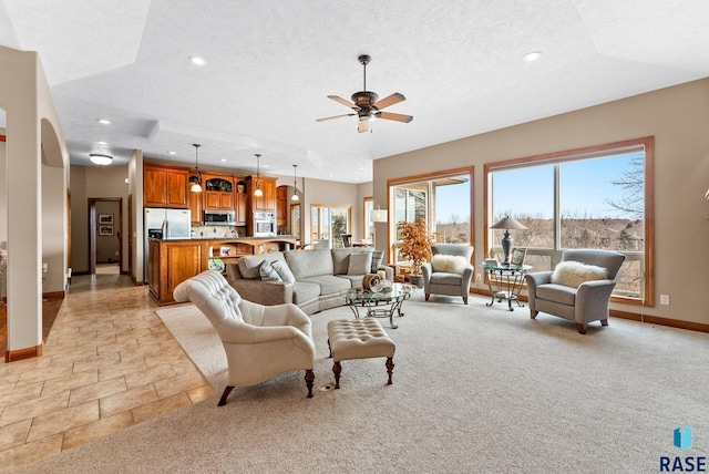 carpeted living room featuring ceiling fan and a textured ceiling