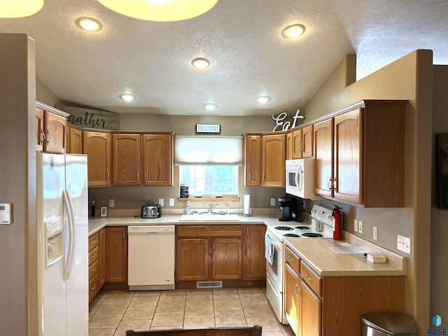 kitchen featuring white appliances, sink, a textured ceiling, and light tile patterned floors