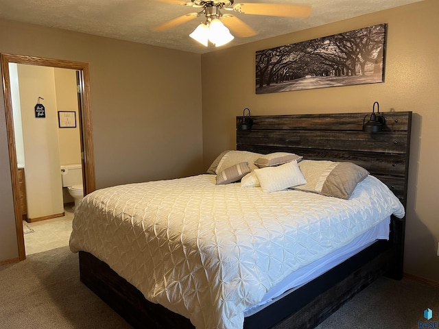 bedroom with ceiling fan, ensuite bathroom, light carpet, and a textured ceiling