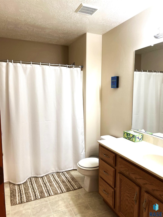 bathroom featuring tile patterned flooring, vanity, toilet, and a textured ceiling