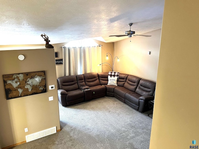 carpeted living room with ceiling fan and a textured ceiling