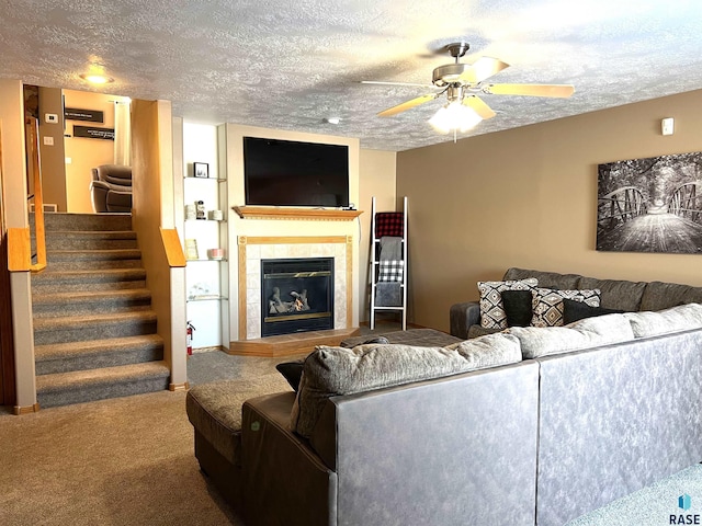 carpeted living room with ceiling fan, a fireplace, and a textured ceiling