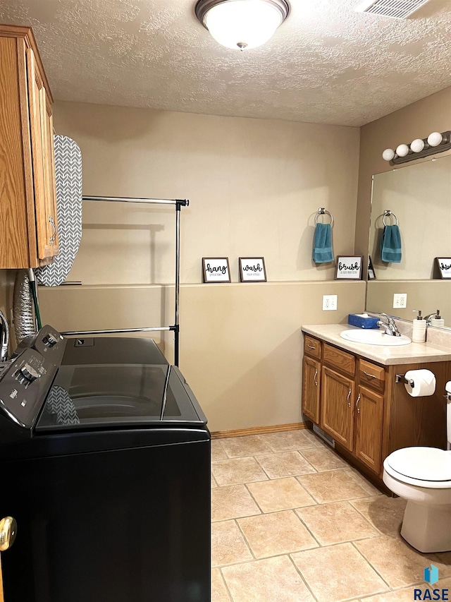 clothes washing area featuring light tile patterned flooring, washer and clothes dryer, sink, and a textured ceiling