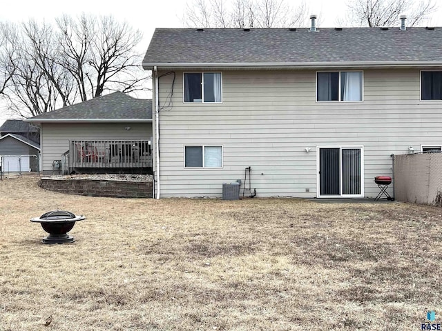 rear view of house featuring cooling unit, an outdoor fire pit, and a lawn