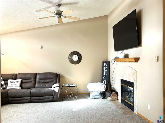 living room featuring a tile fireplace, vaulted ceiling, carpet floors, ceiling fan, and a textured ceiling