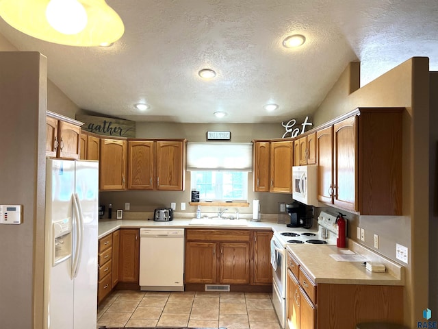 kitchen featuring light tile patterned flooring, white appliances, sink, and a textured ceiling