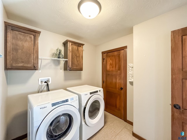 washroom with light tile patterned floors, washing machine and dryer, cabinets, and a textured ceiling