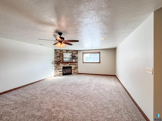 unfurnished living room with ceiling fan, a large fireplace, carpet, and a textured ceiling