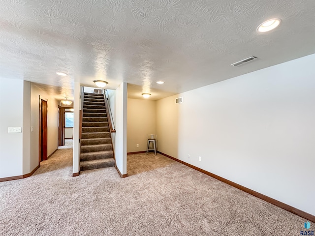 basement featuring light carpet and a textured ceiling